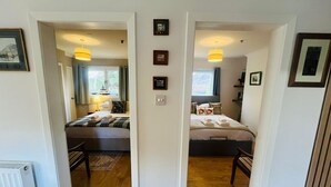 Quarto com duas camas, um radiador e uma porta que dá para outro aposento.