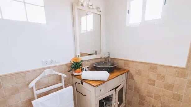 Un bagno con un piano in legno, un lavandino, uno specchio, un porta asciugamani e un armadietto.