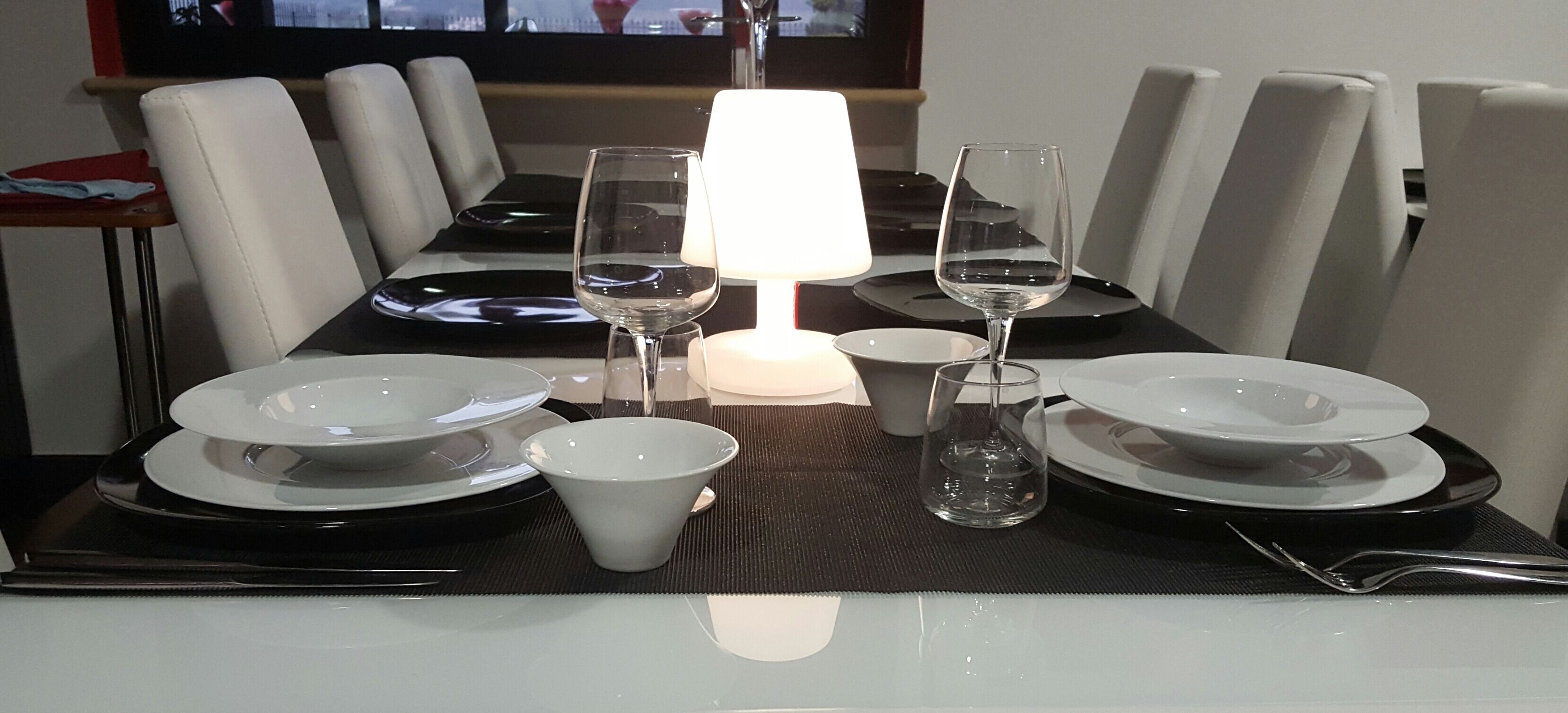 Una mesa de comedor con platos, tazones, vasos y una vela.