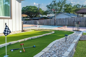 Ein Garten mit Putting Green, kleinem Pool und Holzzaun.