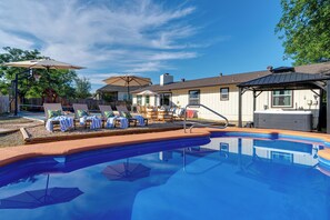 Ein Swimmingpool mit Liegestühlen und Sonnenschirmen, ein Grillbereich und ein Haus mit Schornstein.
