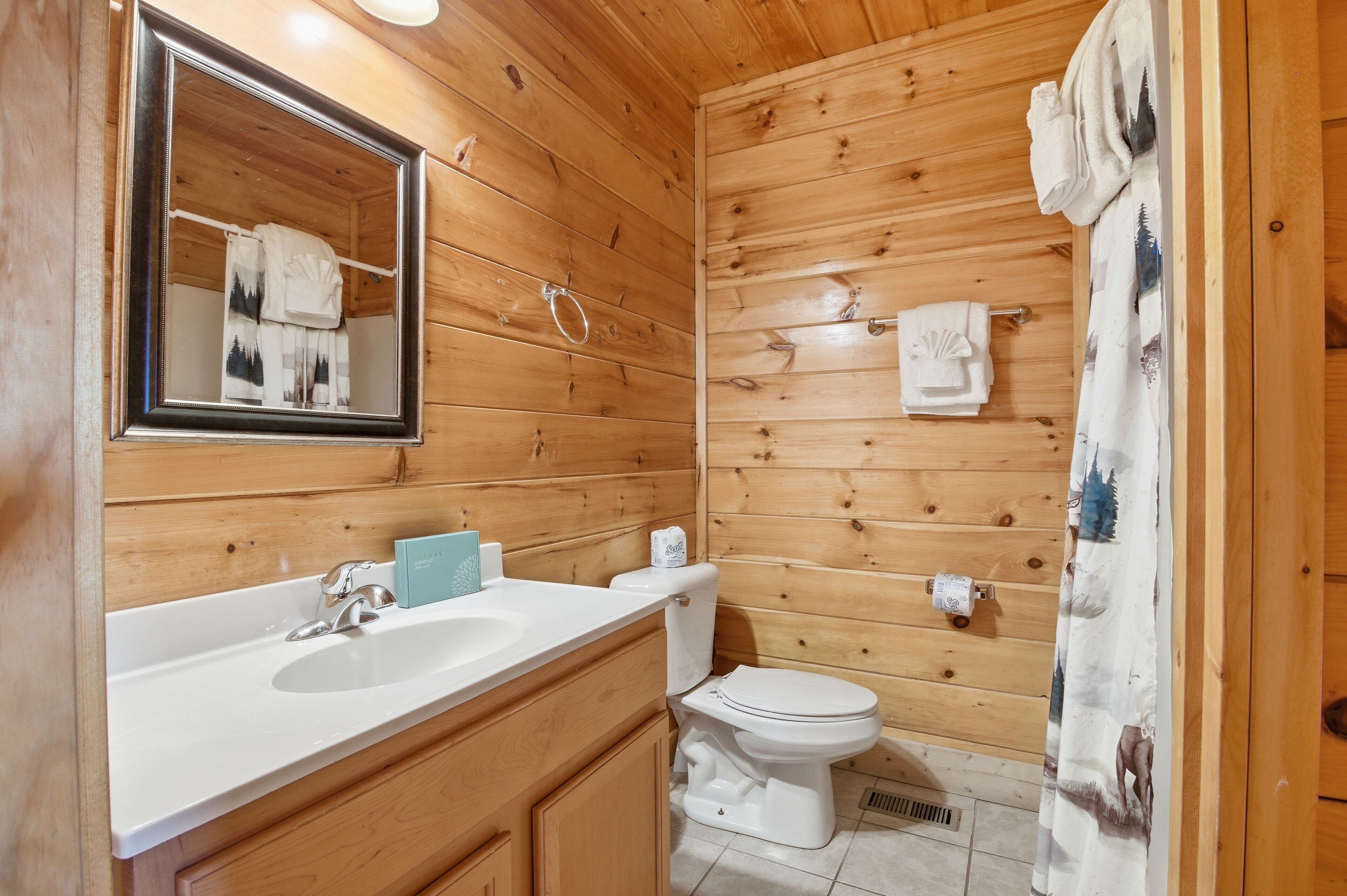 Ein Badezimmer einer Holzhütte mit Waschbecken, Toilette und Spiegel.