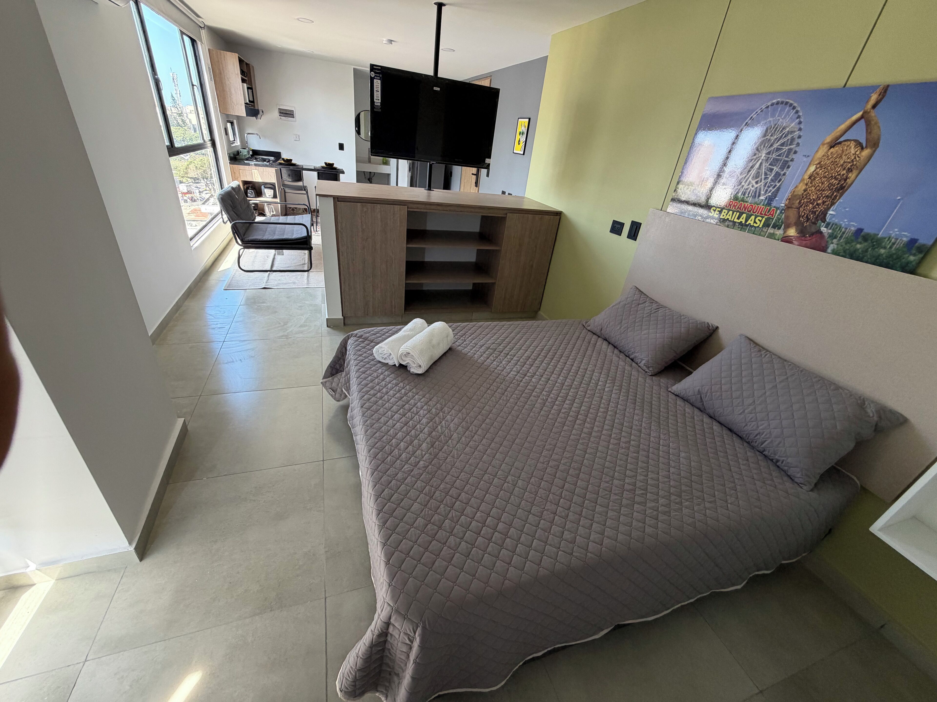 Una habitación de hotel moderna con una cama grande, un escritorio y una kitchenette.