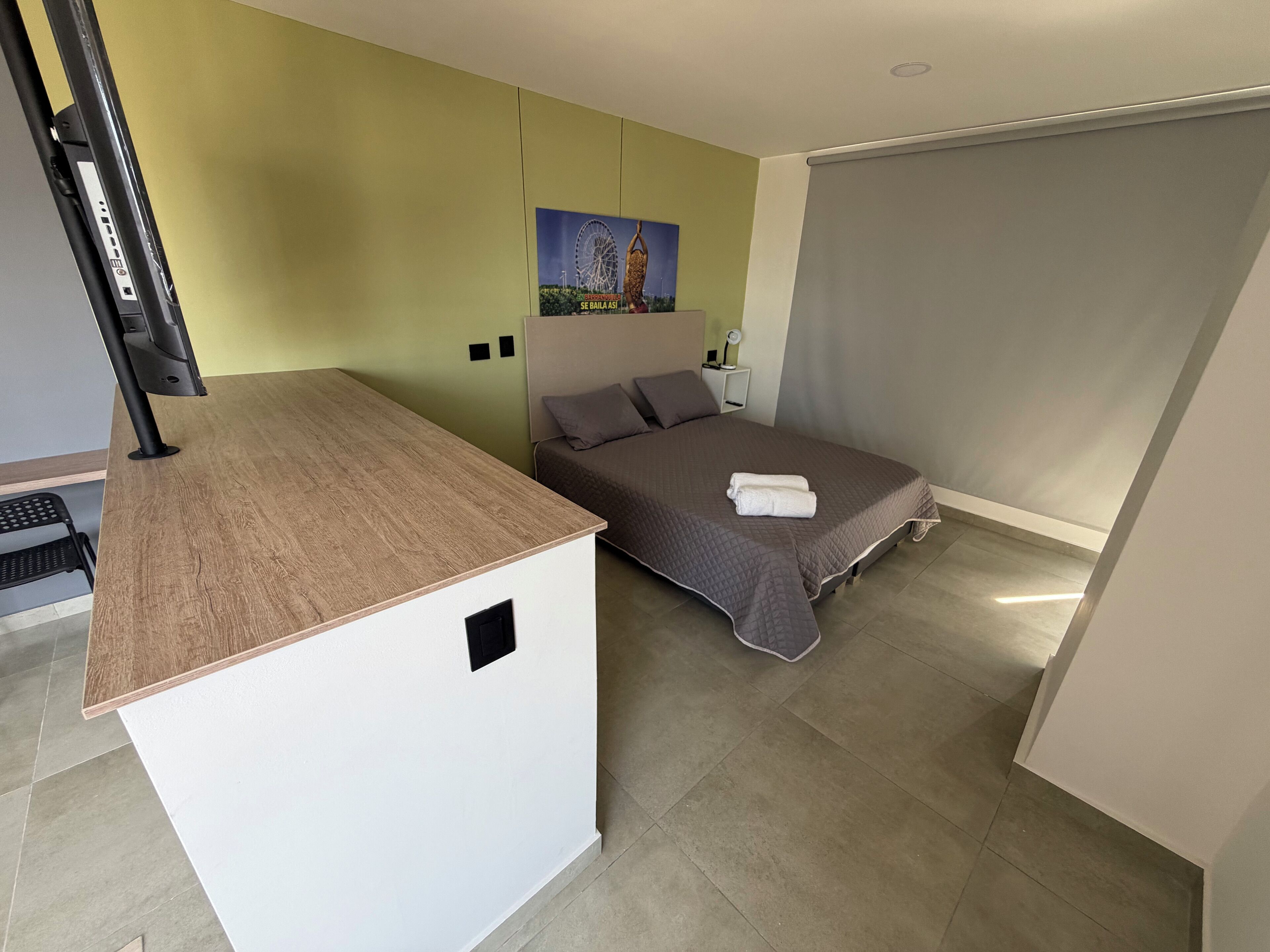 Une chambre d’hôtel de taille modeste, comprenant un lit, un petit bureau et une grande fenêtre.