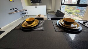 Una cucina moderna con zona pranzo, caratterizzata da un'ampia finestra vista città, una TV a schermo piatto montata e un condizionatore d'aria integrato.