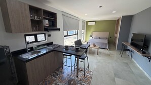 Un ambiente compatto con angolo cottura, un letto, una TV e zona pranzo.