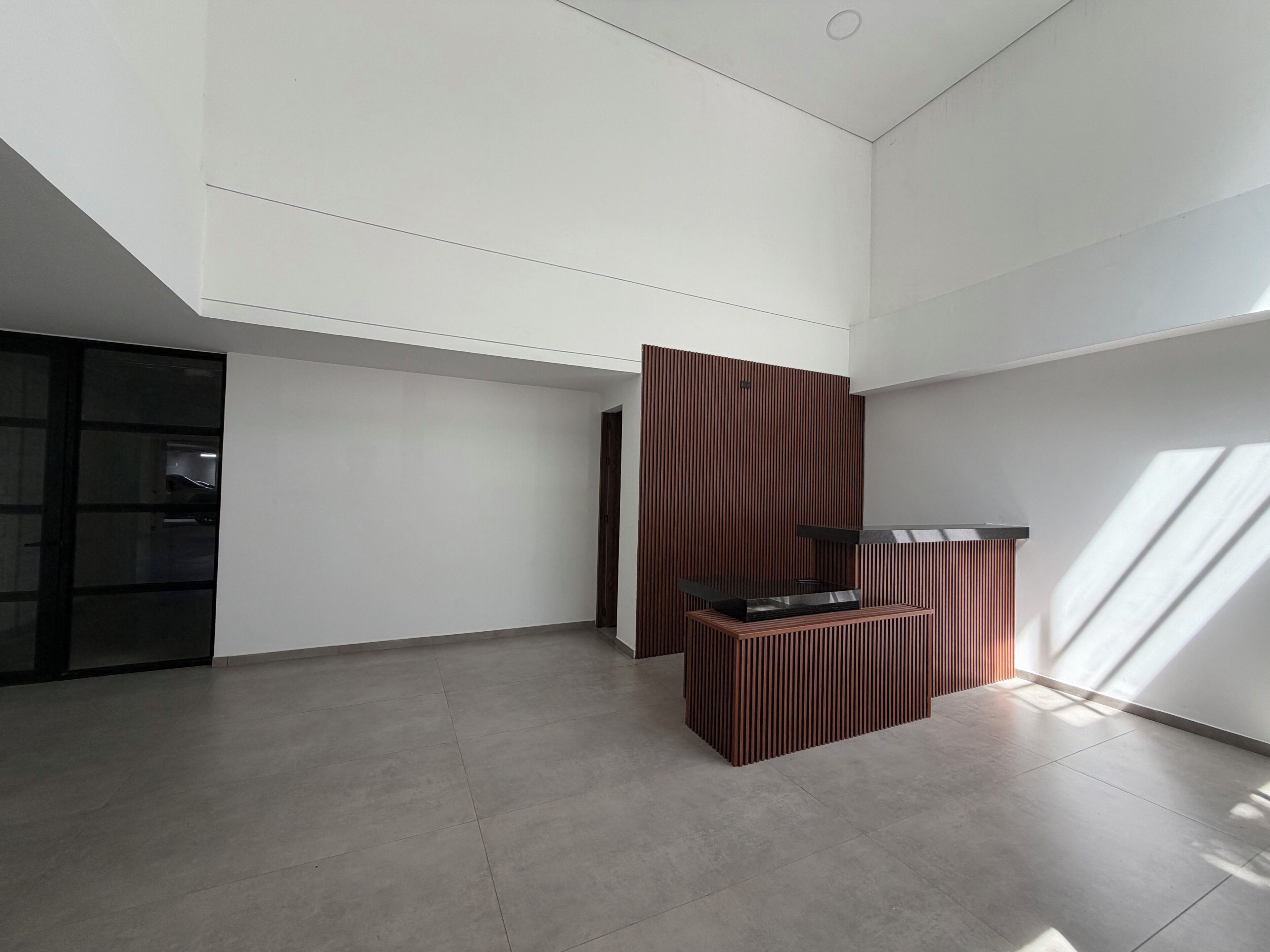 A spacious room with a high ceiling, a large window, and a modern kitchen area.