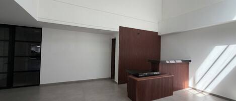 A spacious room with a high ceiling, a large window, and a modern kitchen area.