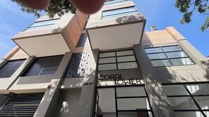 Un edificio moderno con la scritta 'CORAL TOWER' sulla facciata, caratterizzato da un design geometrico, ampie finestre e un tetto piatto.