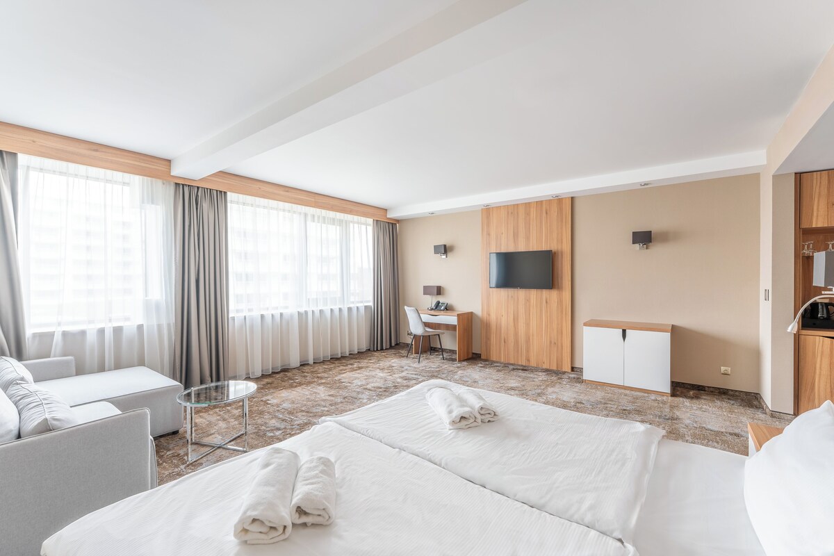 Una camera d'albergo con un letto grande, una scrivania, una sedia e un televisore appeso al muro.