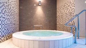 Ett bubbelbad med en metallstege och en vägg med ett mosaikmönster.
