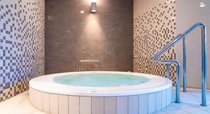 Una vasca idromassaggio con una scala in metallo e un muro decorato con un mosaico.
