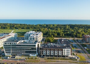 Ein moderner Gebäudekomplex mit mehreren Strukturen, einem Parkplatz und Blick aufs Meer.