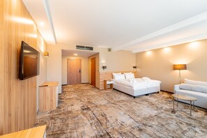 Ein Hotelzimmer mit Bett, Nachttisch, Lampe und einem an der Wand befestigten Fernseher.