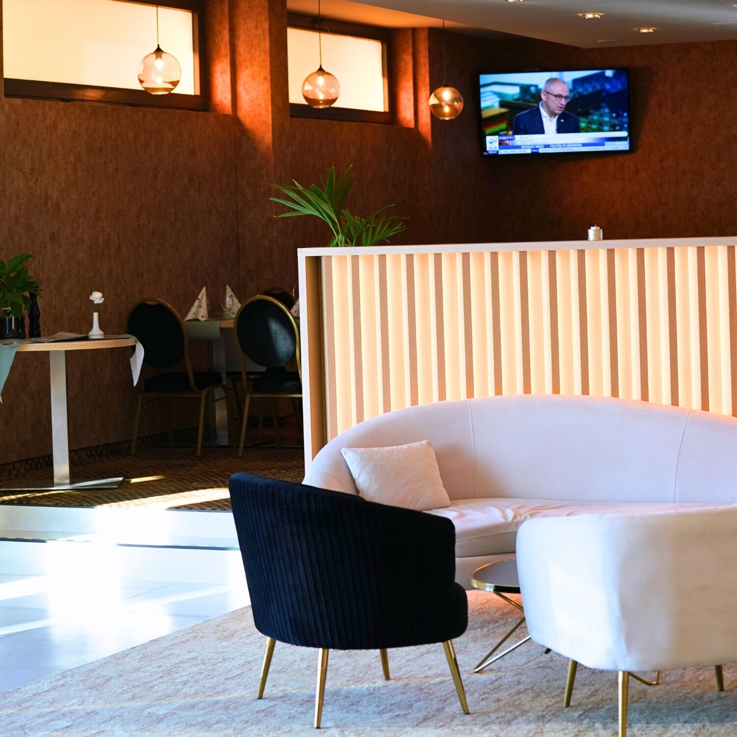 A modern interior with a white sofa, a black armchair, and a television mounted on the wall.