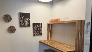 Una zona de bar con mostrador de madera, dos taburetes, luces colgantes y adornos en la pared.