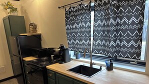 Una cocina moderna con una estufa negra, un lavamanos y una ventana con cortinas estampadas.
