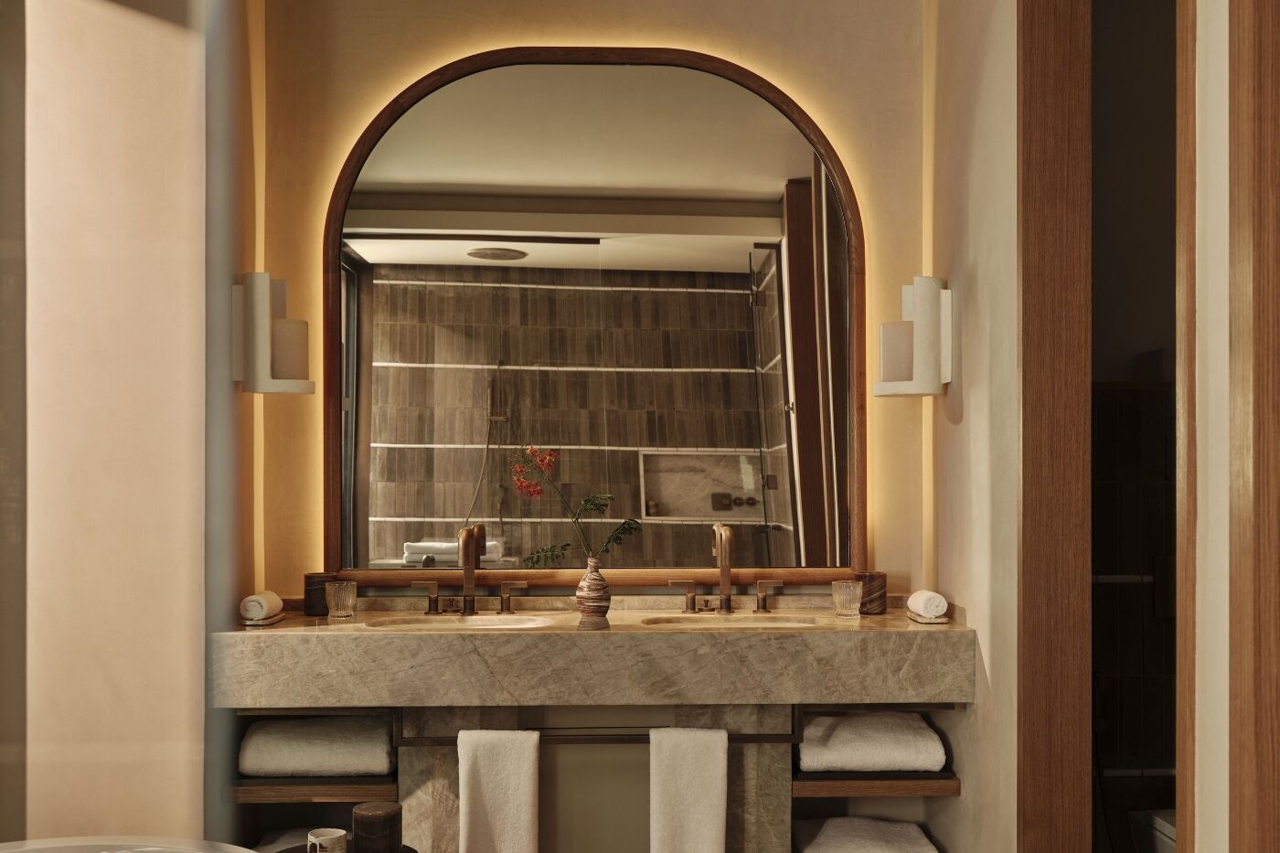 A bathroom with a large mirror, a marble sink, and a towel rack.