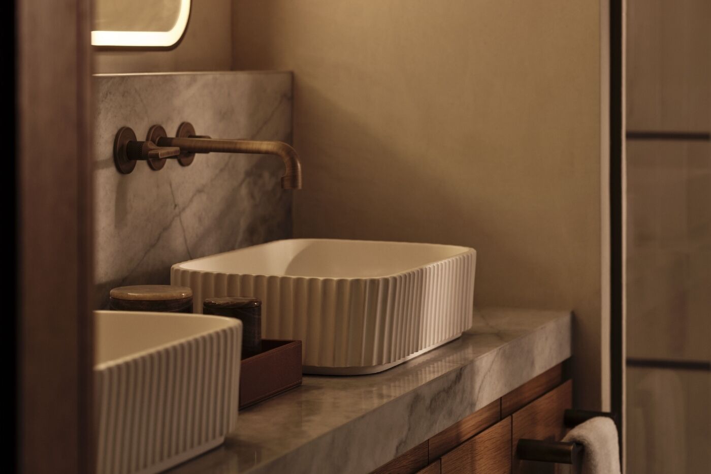 Une salle de bain avec un comptoir en marbre, un lavabo blanc et un robinet mural.
