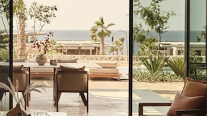 A modern outdoor seating area with a view of the ocean and palm trees.