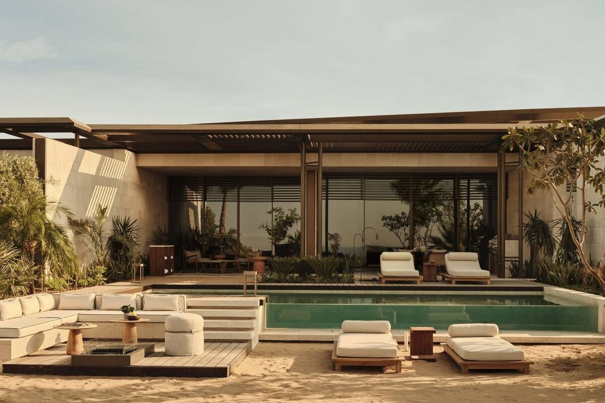A modern outdoor pool area with lounge chairs, a sofa, and a small table.