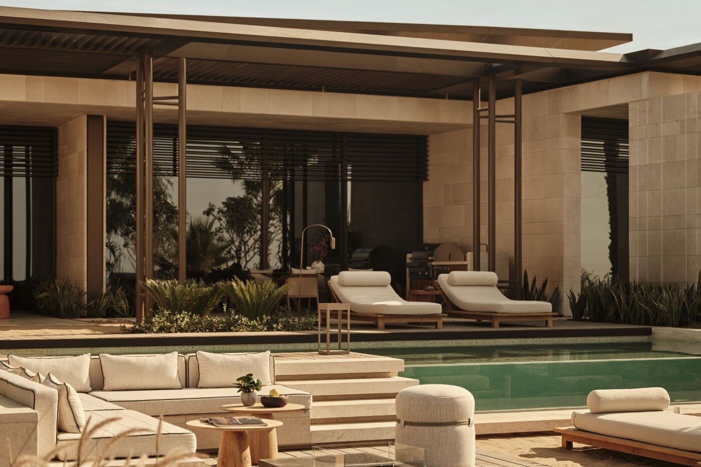 A modern outdoor pool area with lounge chairs, a sofa, and a grill.