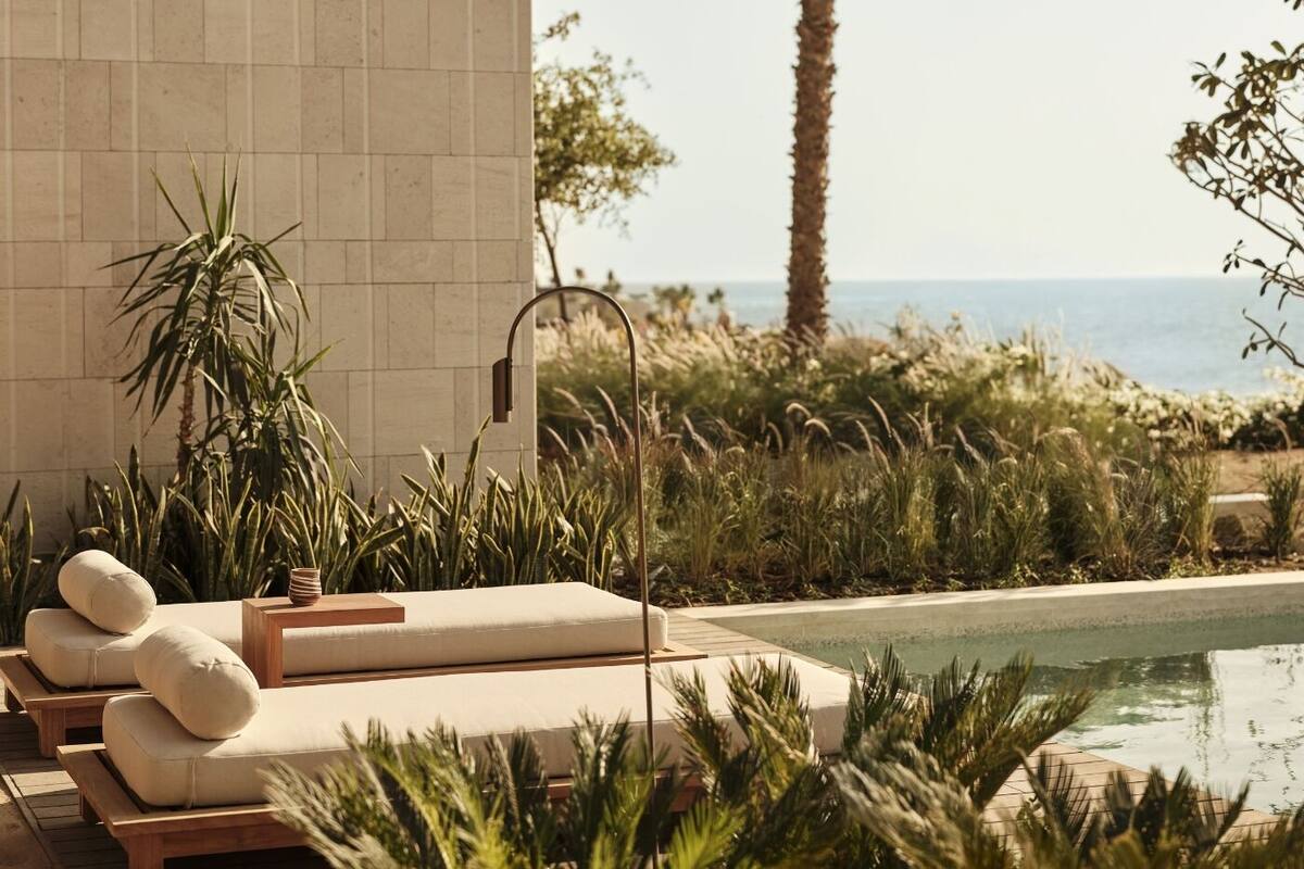 A poolside area with lounge chairs, a small table, and a wall-mounted water feature.
