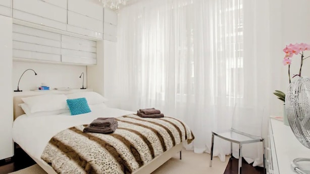 Une chambre à coucher moderne avec un lit, des lampes de chevet, une petite table et une chaise.