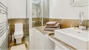 Une salle de bain moderne avec une douche à parois de verre, des toilettes, un lavabo et un miroir.