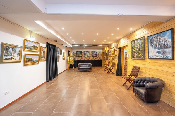 A spacious hallway with a fireplace, wooden walls, and artwork on the walls. - Hotel Liad (Bucharest)