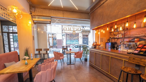 En moderne café med barområde, siddepladser og udsigt til gaden gennem vinduet.
