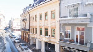 A street view with buildings, parked cars, and a visible storefront with signage. - Hotel Liad (Bucharest)