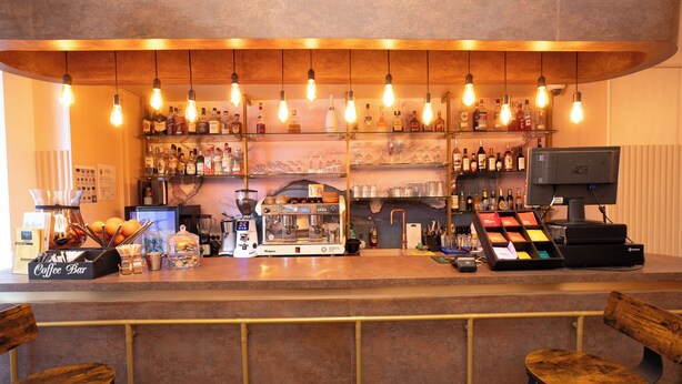 A bar with a coffee station, shelves of liquor, and a television. - Hotel Liad (Bucharest)