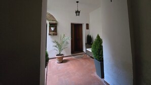 Un couloir avec une plante en pot, une lanterne suspendue et une porte.