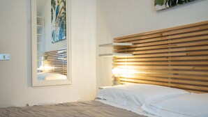 Une chambre à coucher avec un lit, une table de chevet, une lampe, un miroir et une tête de lit en bois.