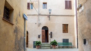 Una calle estrecha con un edificio que tiene una puerta de madera, plantas en macetas y un banco.