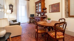 Un comedor con mesa de madera, sillas, un armario y un sofá.