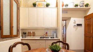 Una cocina con armarios blancos, una mesa de comedor de madera y una planta en maceta sobre la mesa.