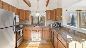 Una cocina con armarios de madera, electrodomésticos de acero inoxidable, encimeras de granito y un tragaluz.