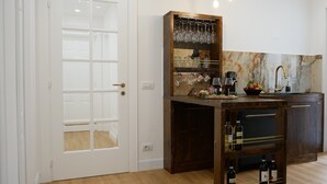 A kitchen with a wooden island, wine glasses, wine bottles, and a sink. - Barocci Home (Rome)