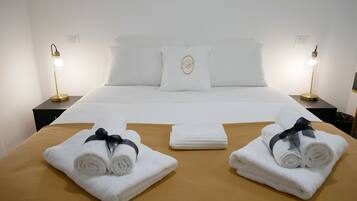 Una habitación de hotel con una cama bien hecha, dos lámparas de noche y toallas sobre la cama.