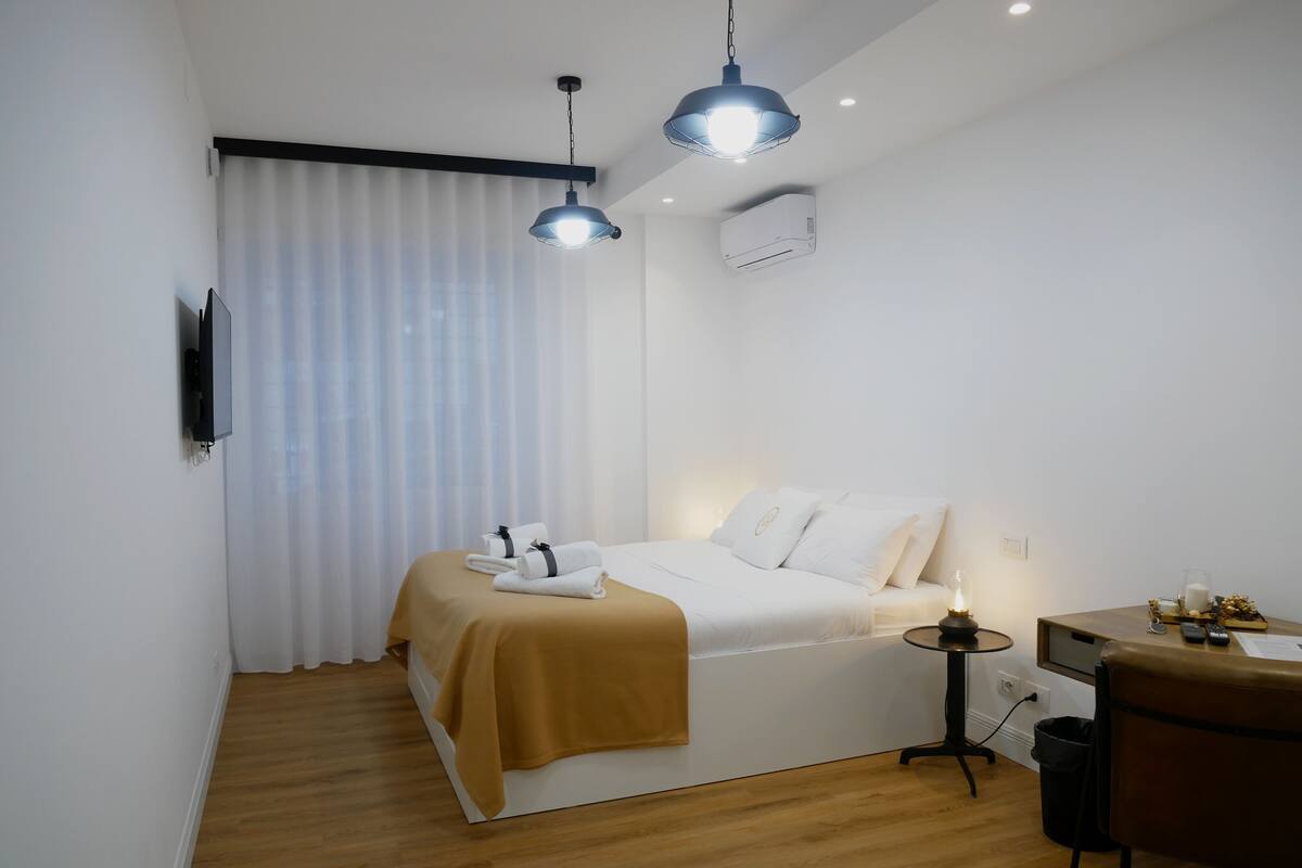 A modern hotel room with a bed, bedside table, and a desk area.
