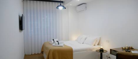 A modern hotel room with a bed, bedside table, and a desk area.