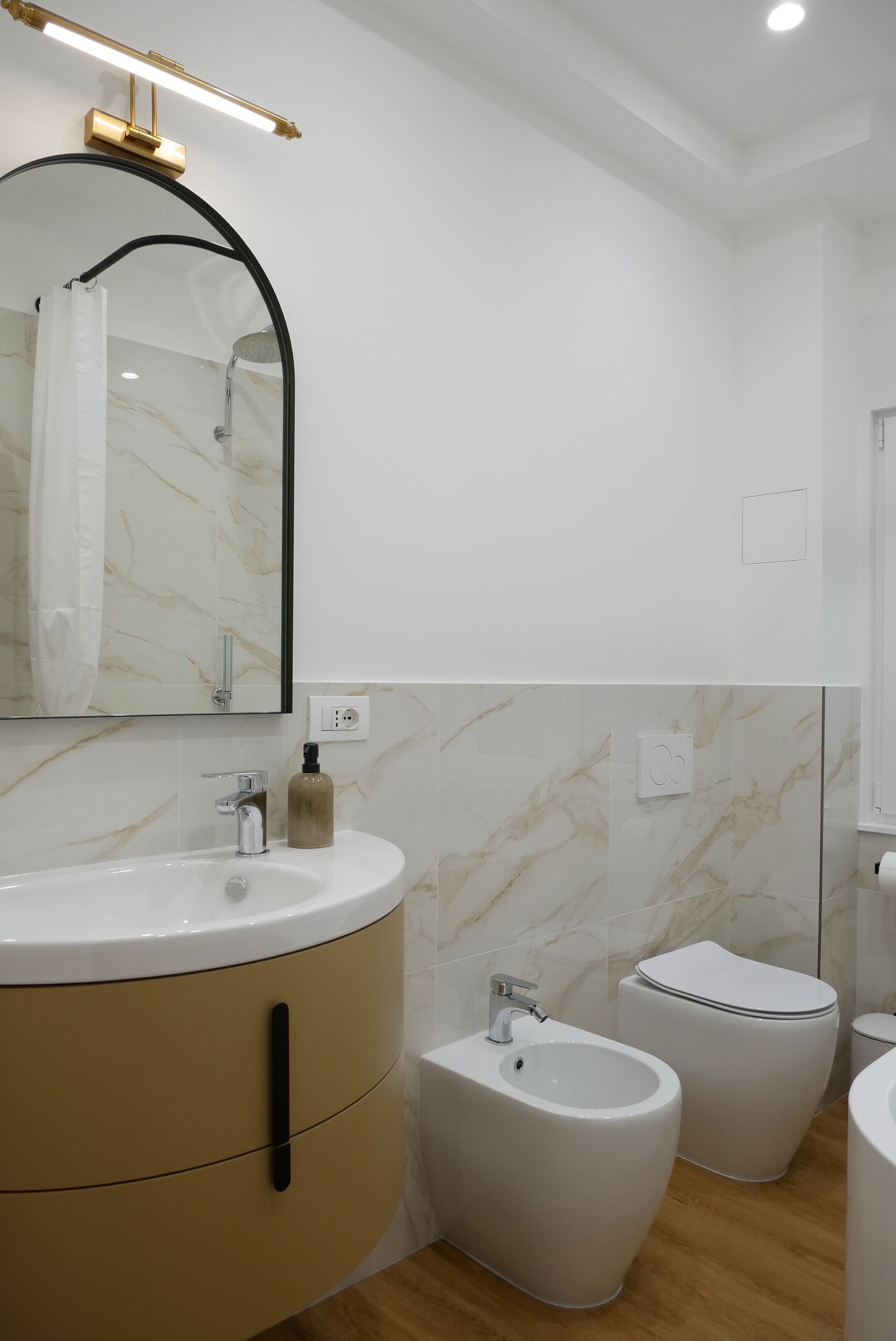 A modern bathroom with a marble vanity, bidet, and a large mirror.
