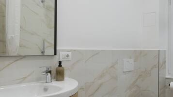 A modern bathroom with a marble vanity, bidet, and a large mirror.