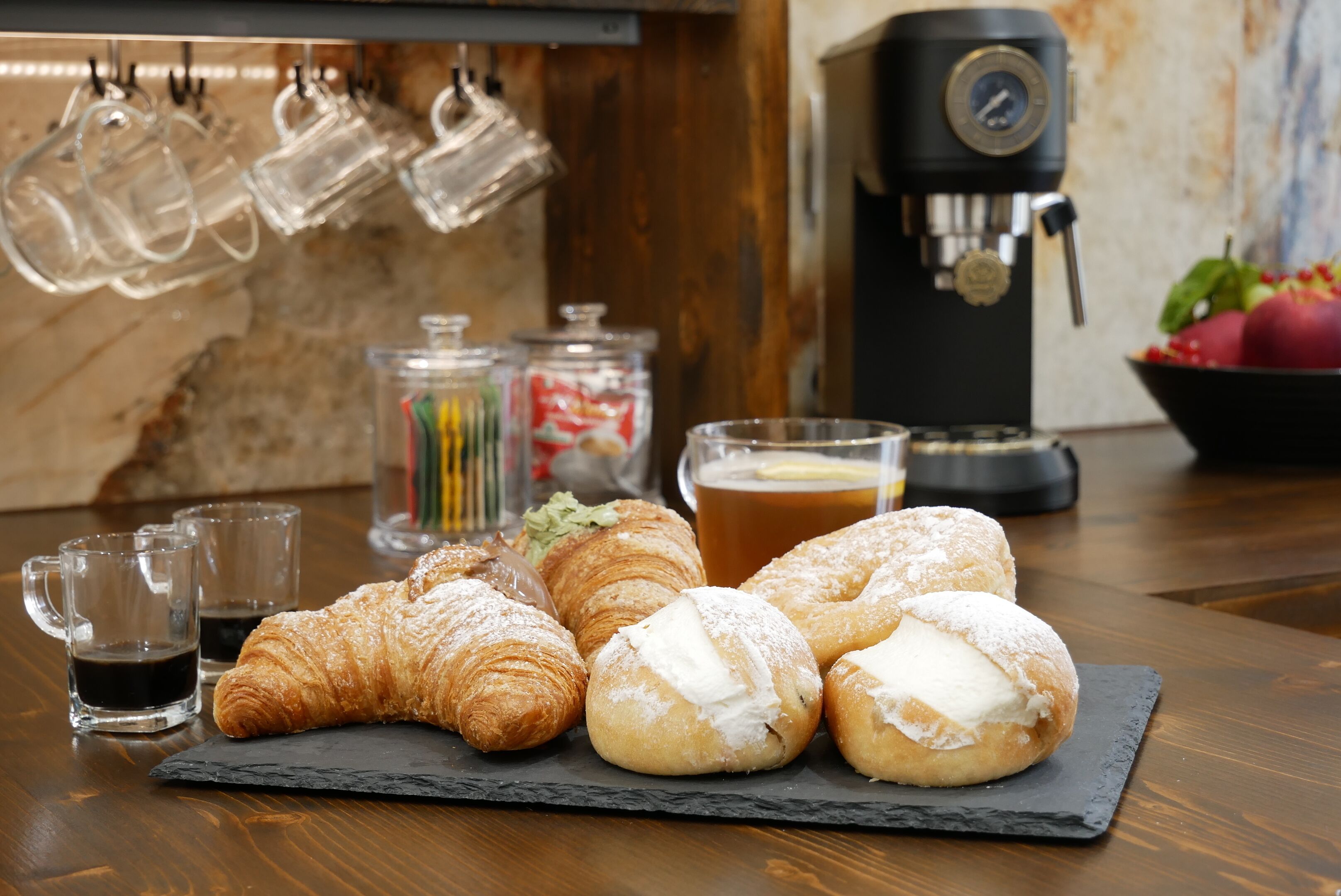 A table with pastries, coffee, and glasses.