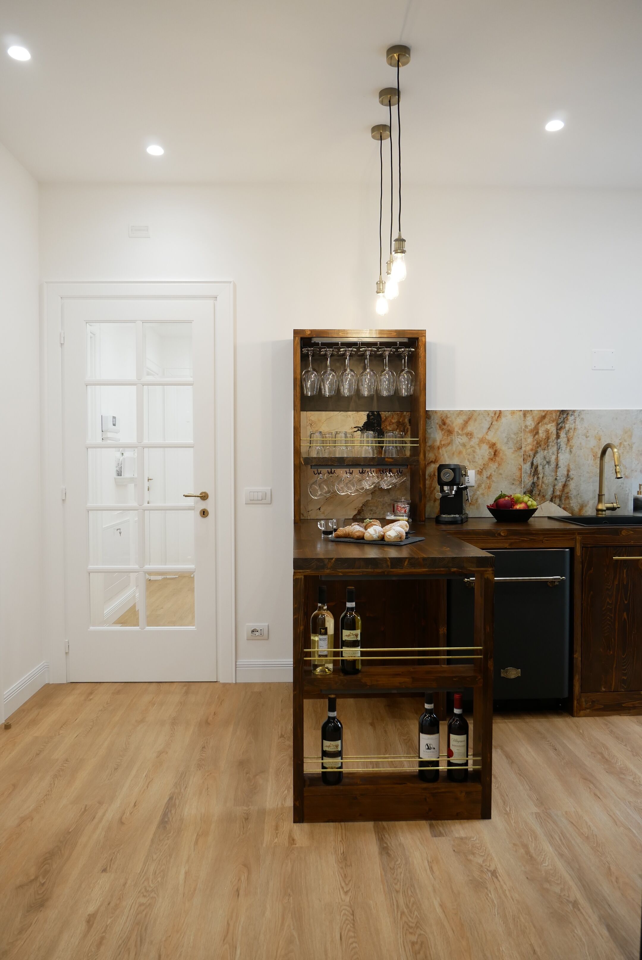 Cozinha com ilha de madeira, garrafas de vinho e máquina de café.