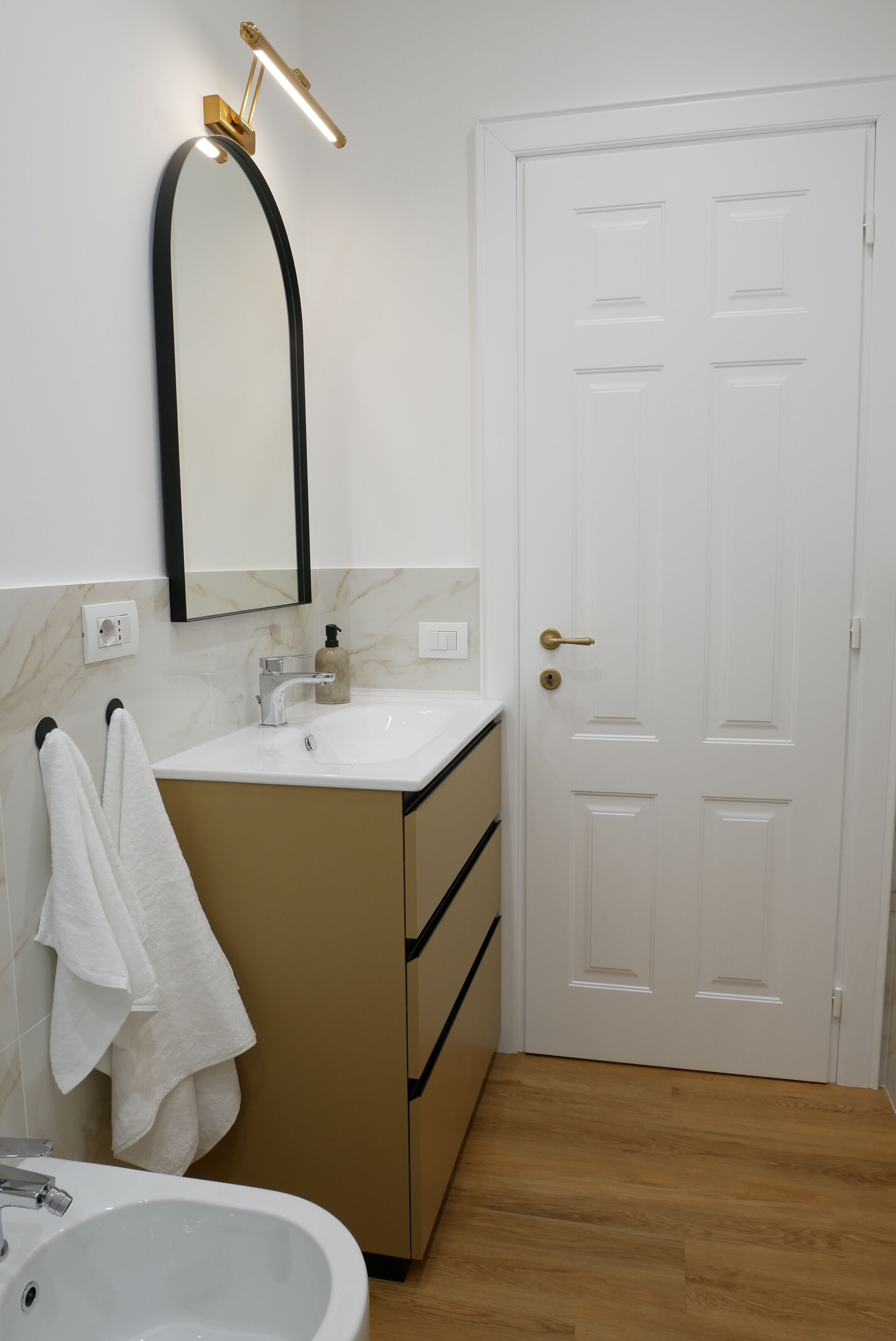 A bathroom with a white sink, a mirror, a towel rack, and a door.