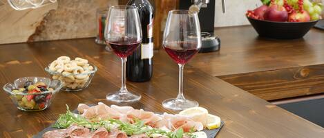 A wooden table with a charcuterie board, wine glasses, and a bowl of olives.