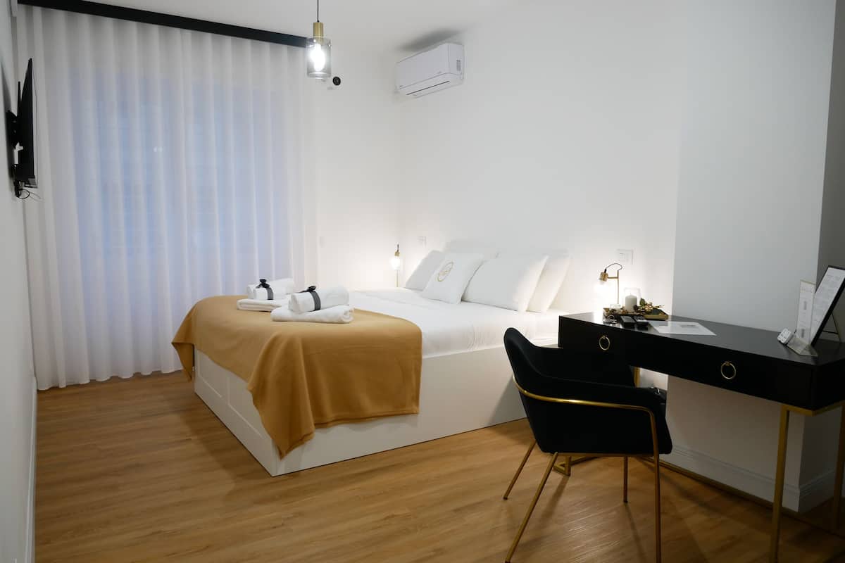 A hotel room with a bed, a desk, a chair, and a window with curtains.